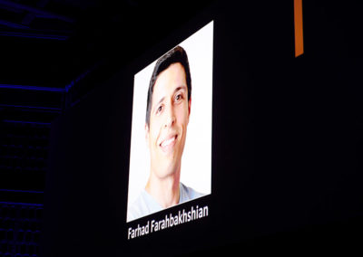 A large screen recognizes Farhad Farahbakhshian at a OneSource Strategy alumni event