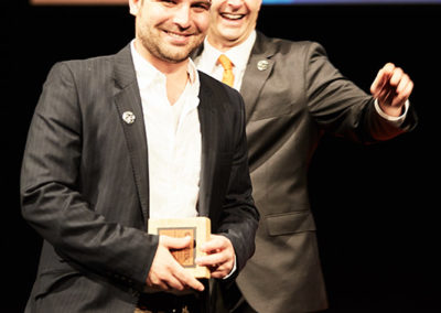 Two men smile while one receives a commendation box at a OneSource Strategy alumni event