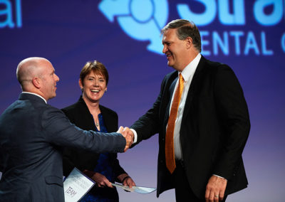 Two Men Shake Hands on Stage at a OneSource Strategy Event