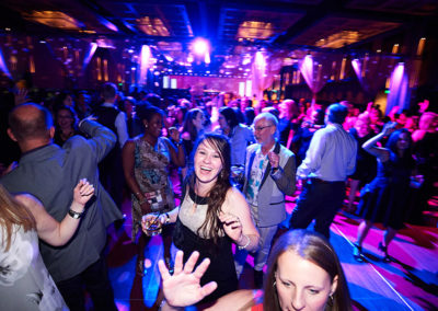 A Woman Smiling While Dancing in a Crowd at a OneSource Strategy Event Party