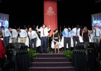 A line of graduates go through a white coat ceremony at a OneSource Strategy higher education event