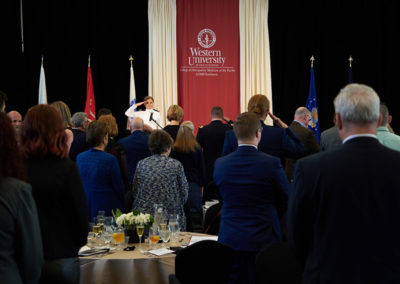 A person salutes to a crowd at a OneSource Strategy higher education ceremony
