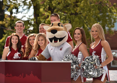 A cougar mascot with a cheerleading squad outdoors at a OneSource Strategy higher education celebration