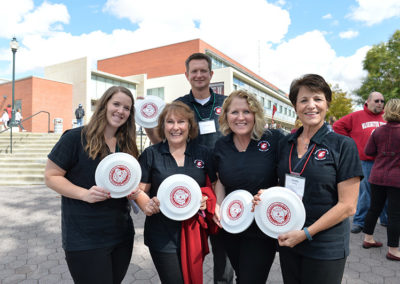A group of people present branded frisbees at an outdoor celebration put on by OneSource Strategy