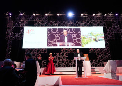 A man presents at a podium onstage at a OneSource Strategy higher education gala event