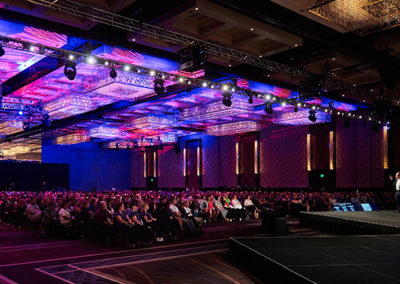 Wide Shot of a Crowd of People Listening to a Man Present on Stage at a OneSource Strategy Event