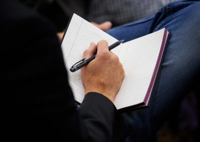 A Person Ready to Take Notes in a New Notebook in Their Lap at a OneSource Strategy Event